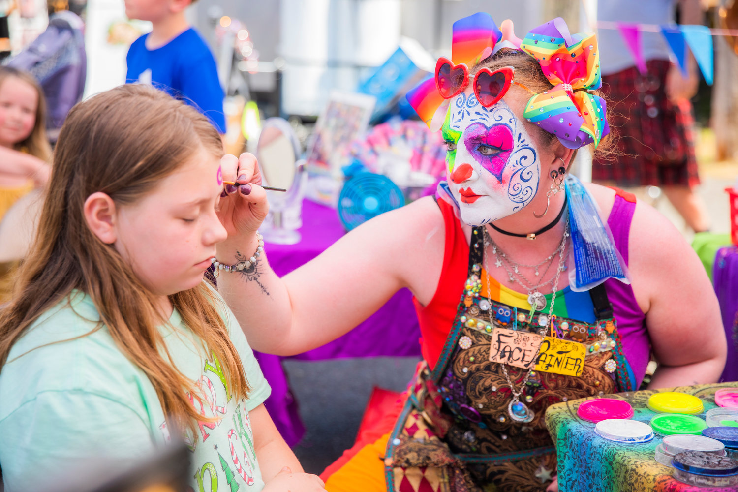 Anabelle Thomas, 9, receives artwork from Ann McRann at a table offering face painting Saturday during Chehalis Fest.